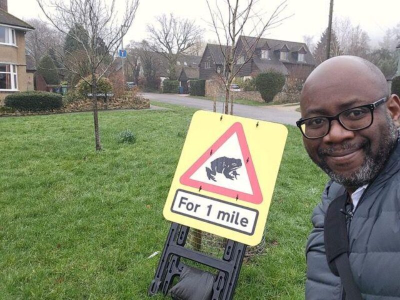 Cllr Chewe Munkonge in front of one of the Toad Signs in Risinghurst.